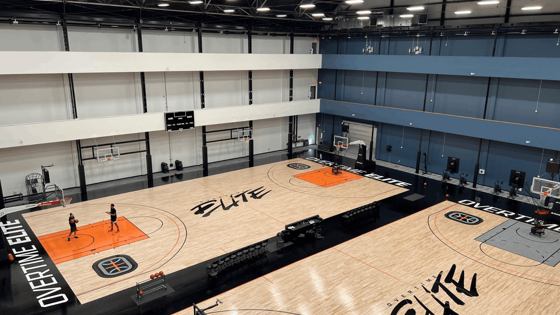 a spacious indoor basketball training facility with multiple full size courts hoops training equipment and high ceilings under bright lights
