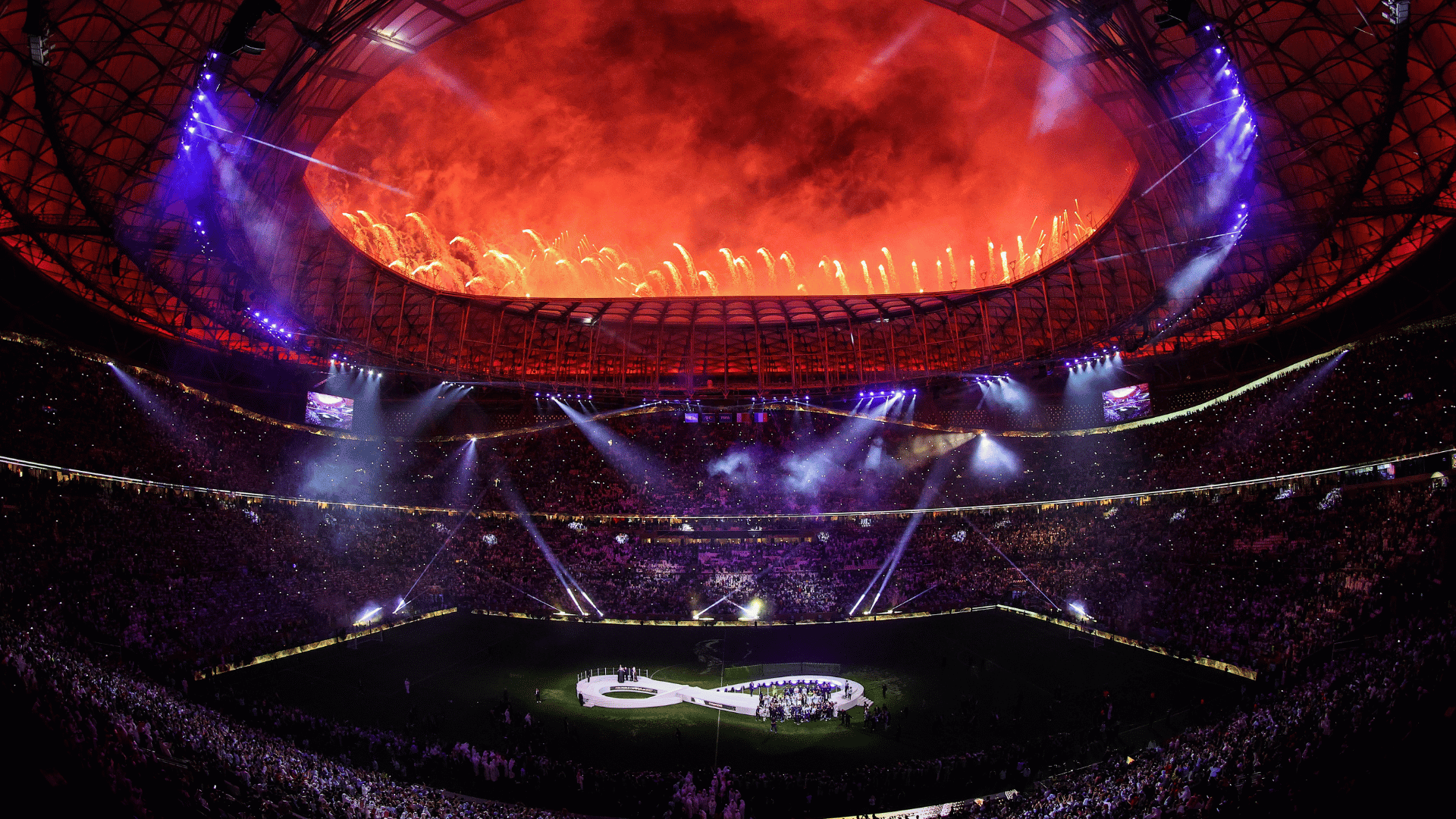 brightly illuminated red and purple stage design set up inside a large sports stadium