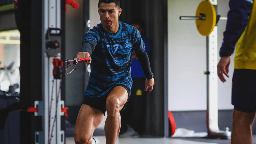 christiano ronaldo performing a resisted forward lunge with a cable attachment during athletic training in a professional gym