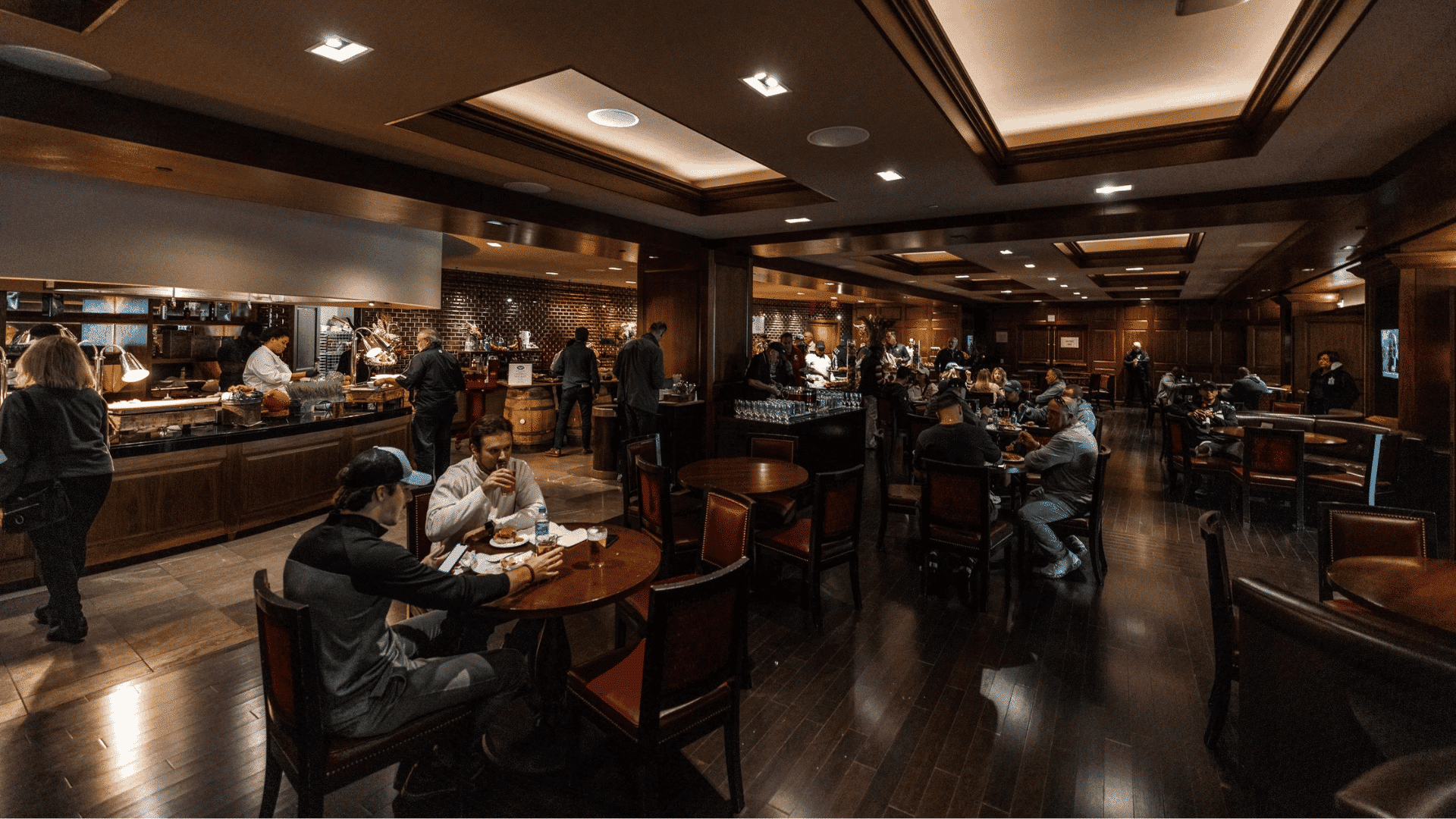 dimly lit premium club lounge inside the stadium filled with many patrons seated at tables