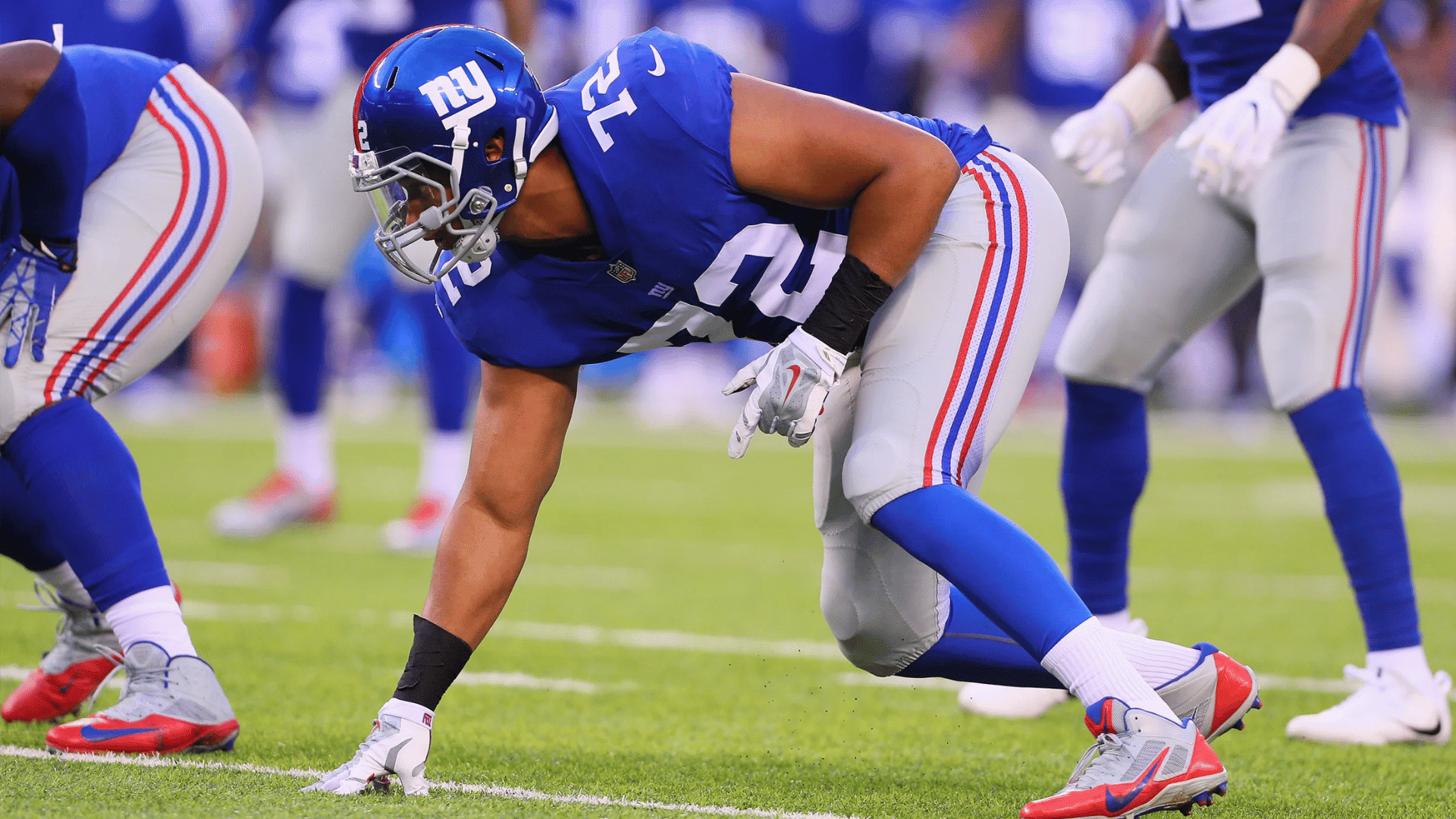 football defensive lineman crouching at the line of scrimmage before the snap during a professional game