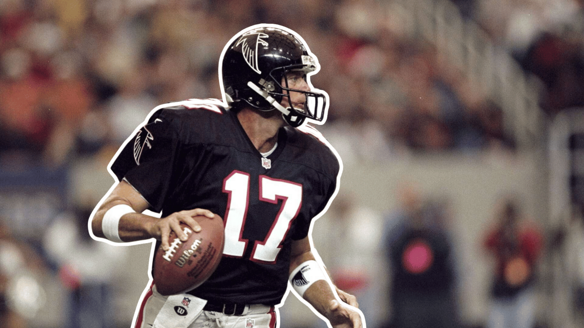 football player in a black jersey and helmet runs with the football while looking downfield during a game in a crowded stadium
