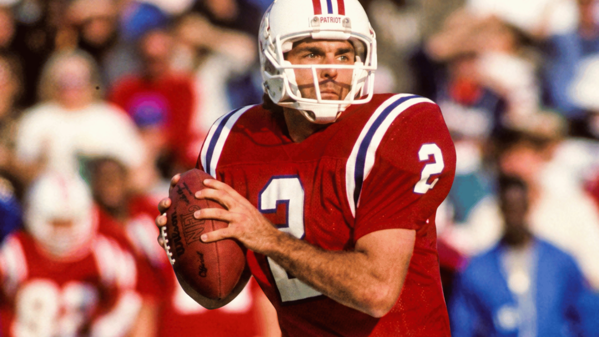football player in a red jersey and white helmet holds the football ready to pass while scanning the field during the game (1)