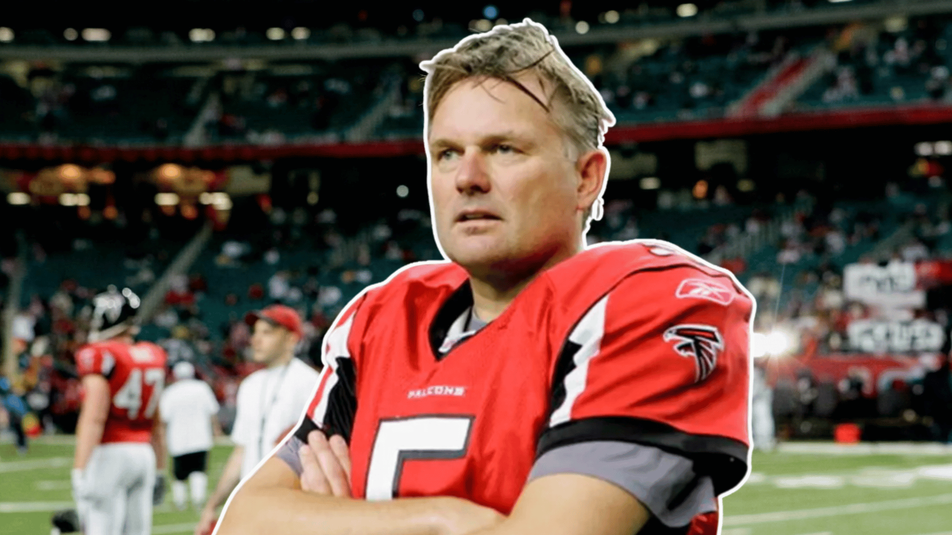 football player in a red jersey stands on the field with arms crossed looking ahead before the game in a large stadium
