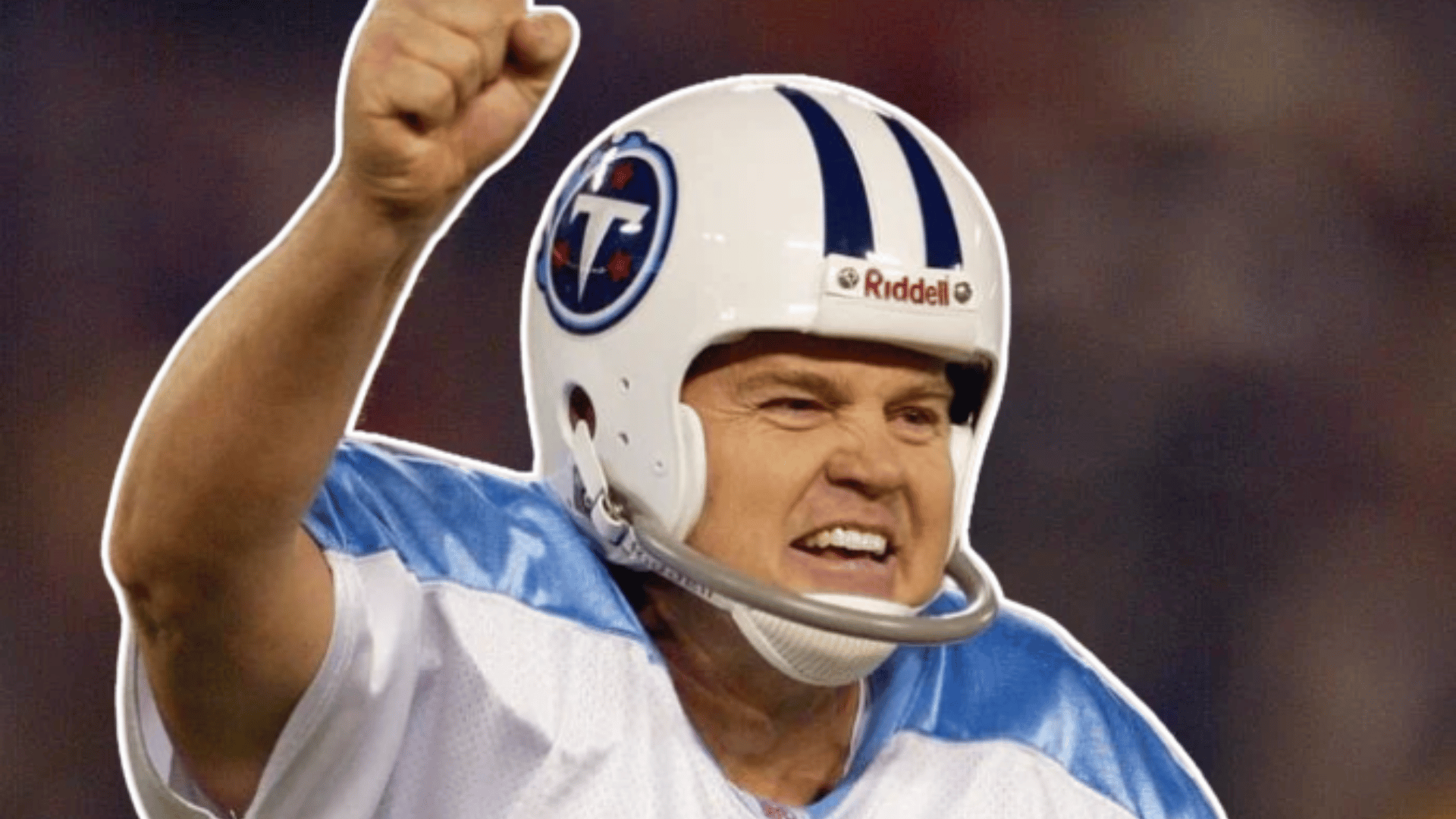 football player in a white and light blue jersey raises a clenched fist while celebrating during a game wearing a white helmet