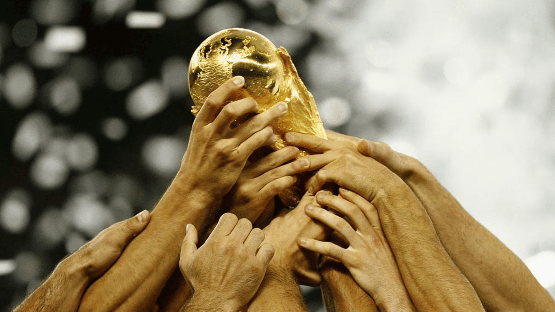 multiple hands lift the world cup trophy in celebration during a championship victory moment with confetti in background