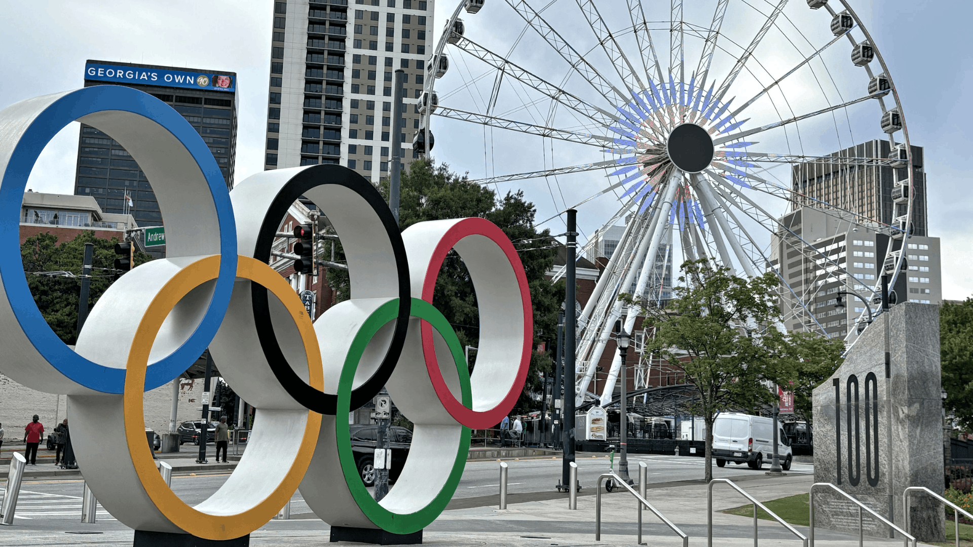olympic rings sculpture at centennial olympic park with a ferris wheel and atlanta skyline buildings (1)