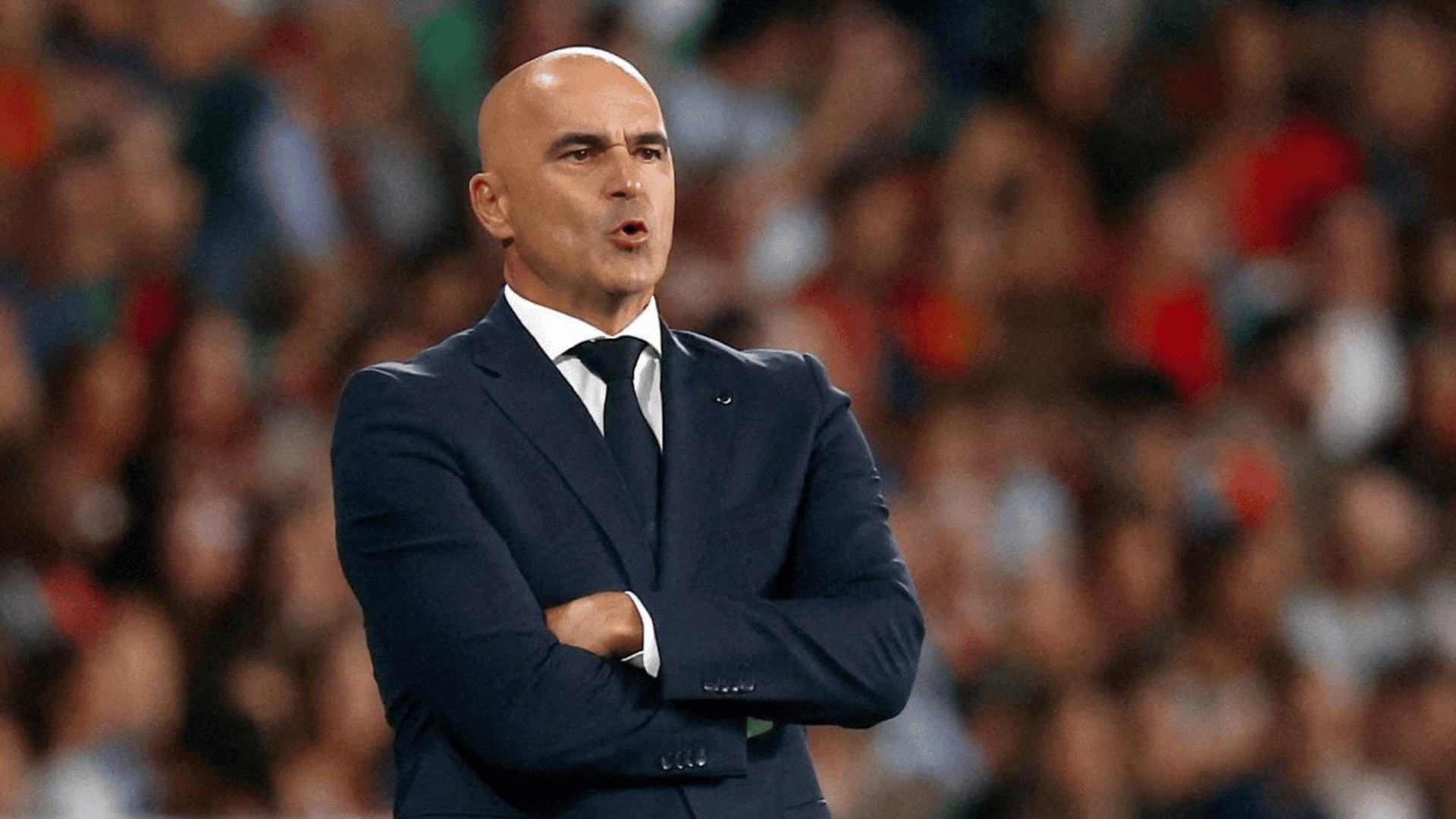 professional soccer team manager standing on the sidelines during a football match