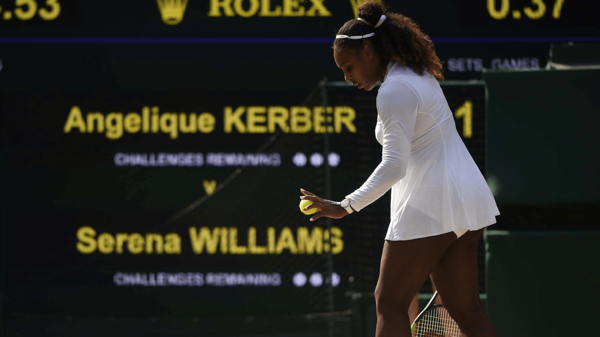 serena williams in white outfit bounces a ball before serving during a match with the scoreboard visible in the background