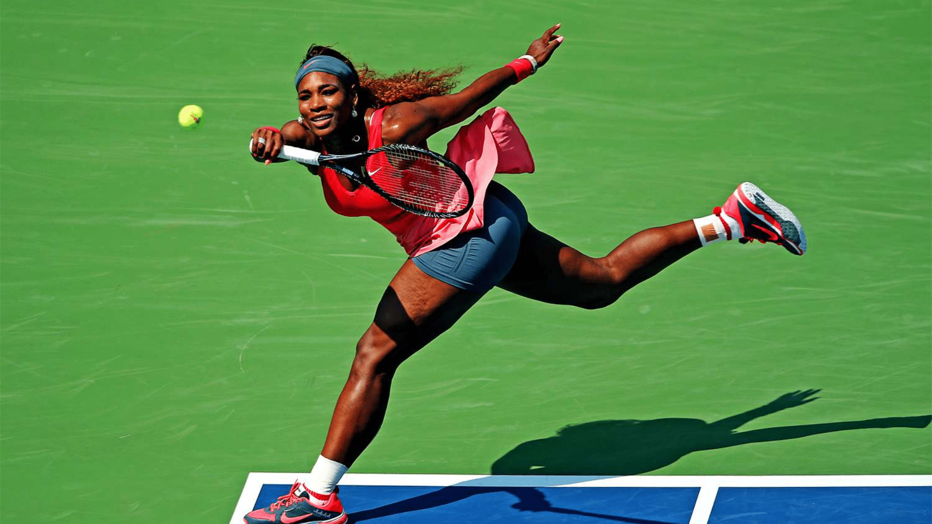 serena williams stretching to return a shot during a match while reaching for the ball on a bright outdoor court