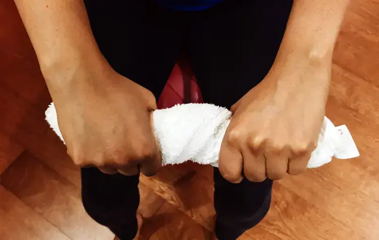 Hands gripping a white towel tightly on wooden floor background