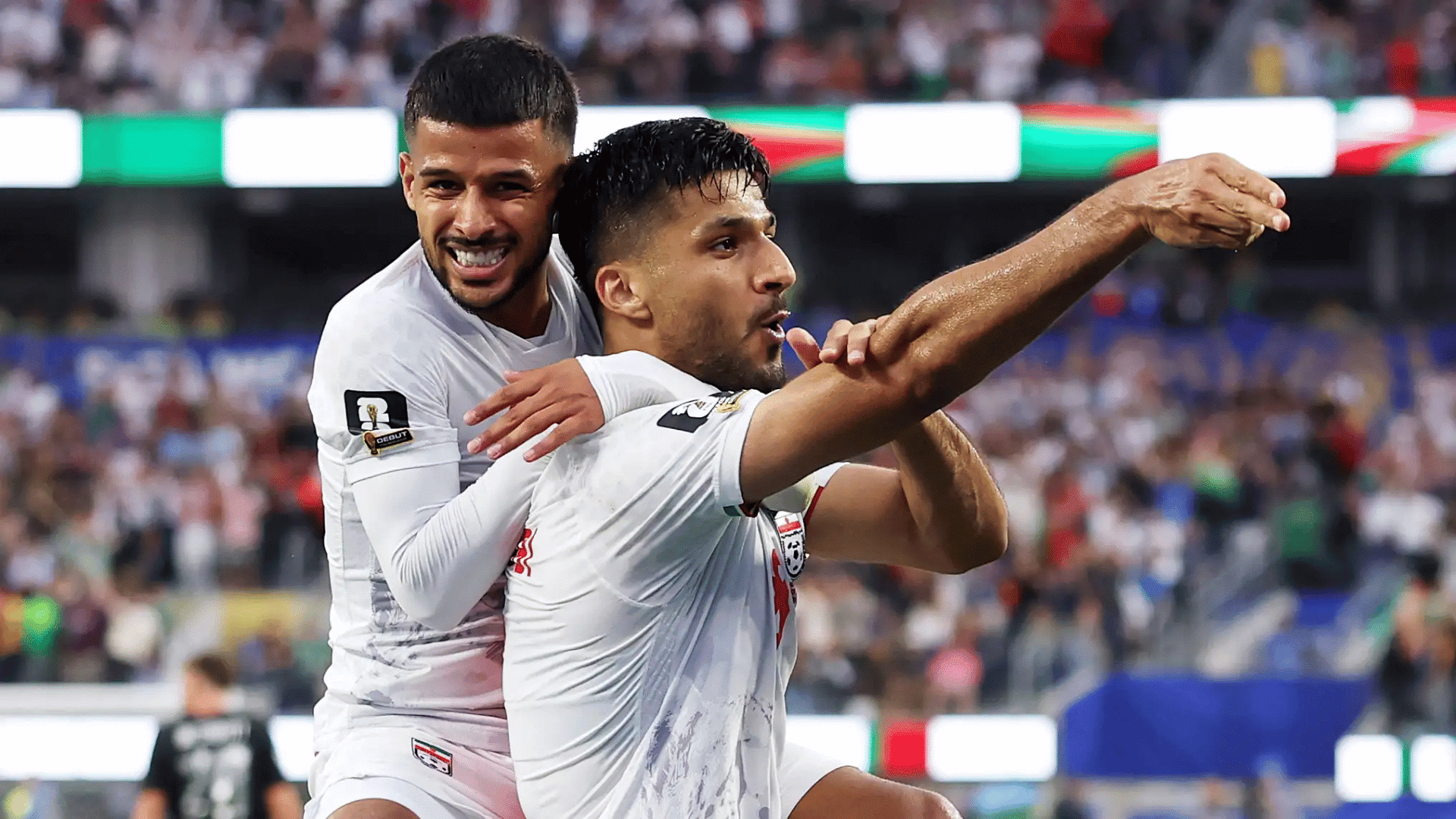 two soccer players in white team jerseys celebrating a goal during a football match