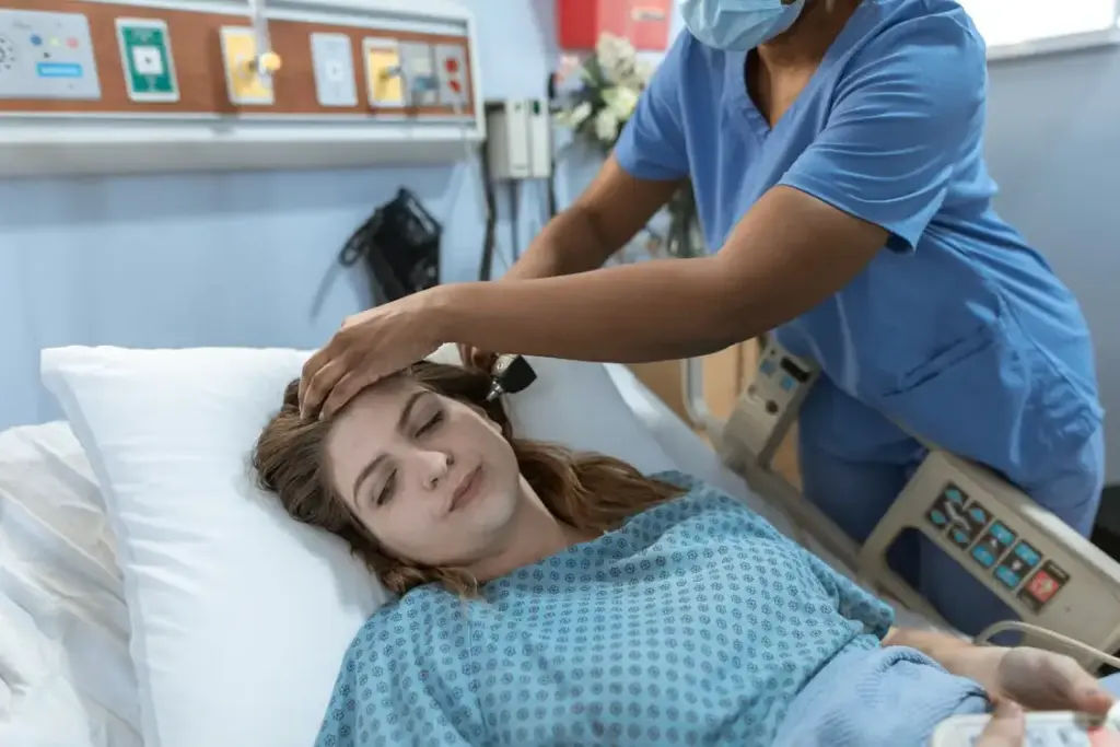 Nurse adjusting patient's pillow in hospital room with medical equipment visible
