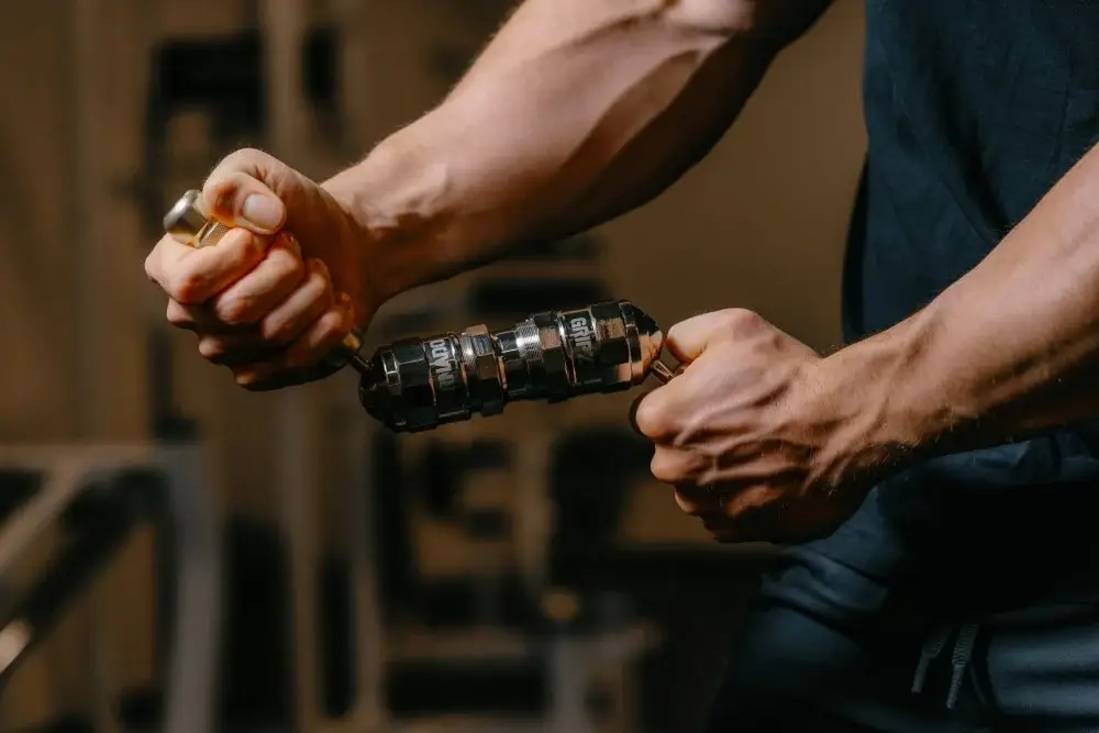 Person squeezing hand grip exerciser in dimly lit gym environment