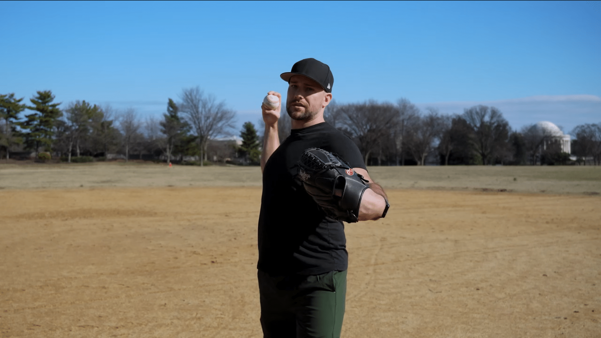 a baseball player holding a glove and baseball in a throwing stance on an open field while demonstrating proper pitching mechanics