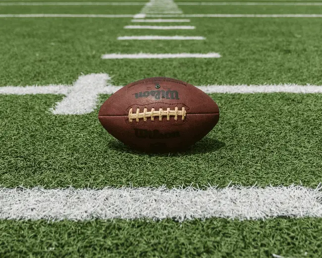 Football resting on green field with white yard lines