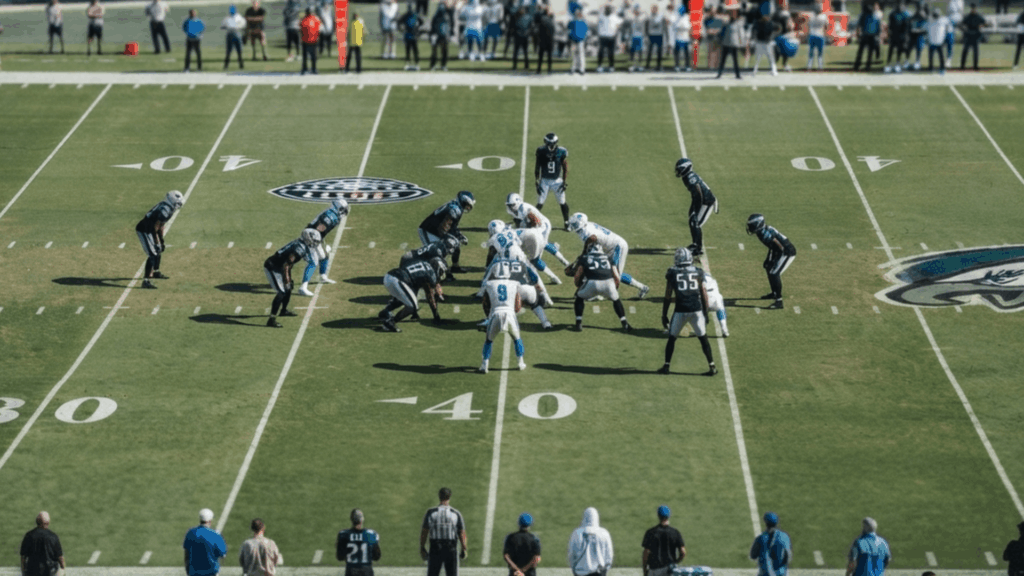 american football teams lined up at the line of scrimmage before the snap during a professional game in a packed stadium