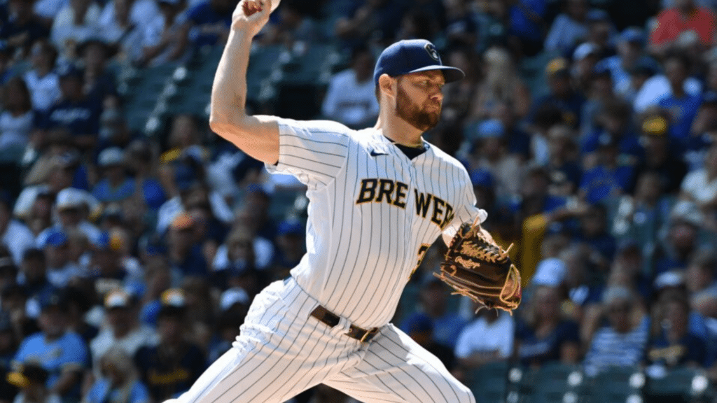 baseball pitcher in brewers uniform throws a pitch during a game with fans filling the stadium seats in the background