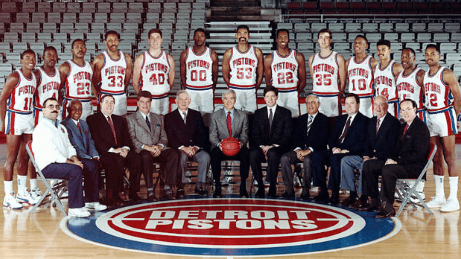 detroit pistons basketball team posing for a formal group photo on the court with coaches and staff seated in front