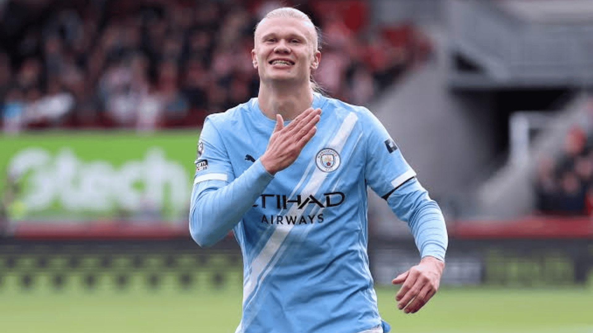 erling haaland wearing a light blue club jersey celebrating on the field during a stadium match