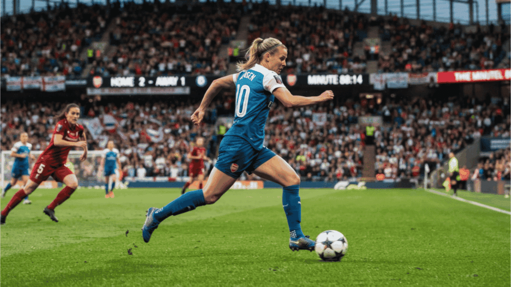 female soccer player sprints with the ball during a match as opponents chase across the field before a packed crowd
