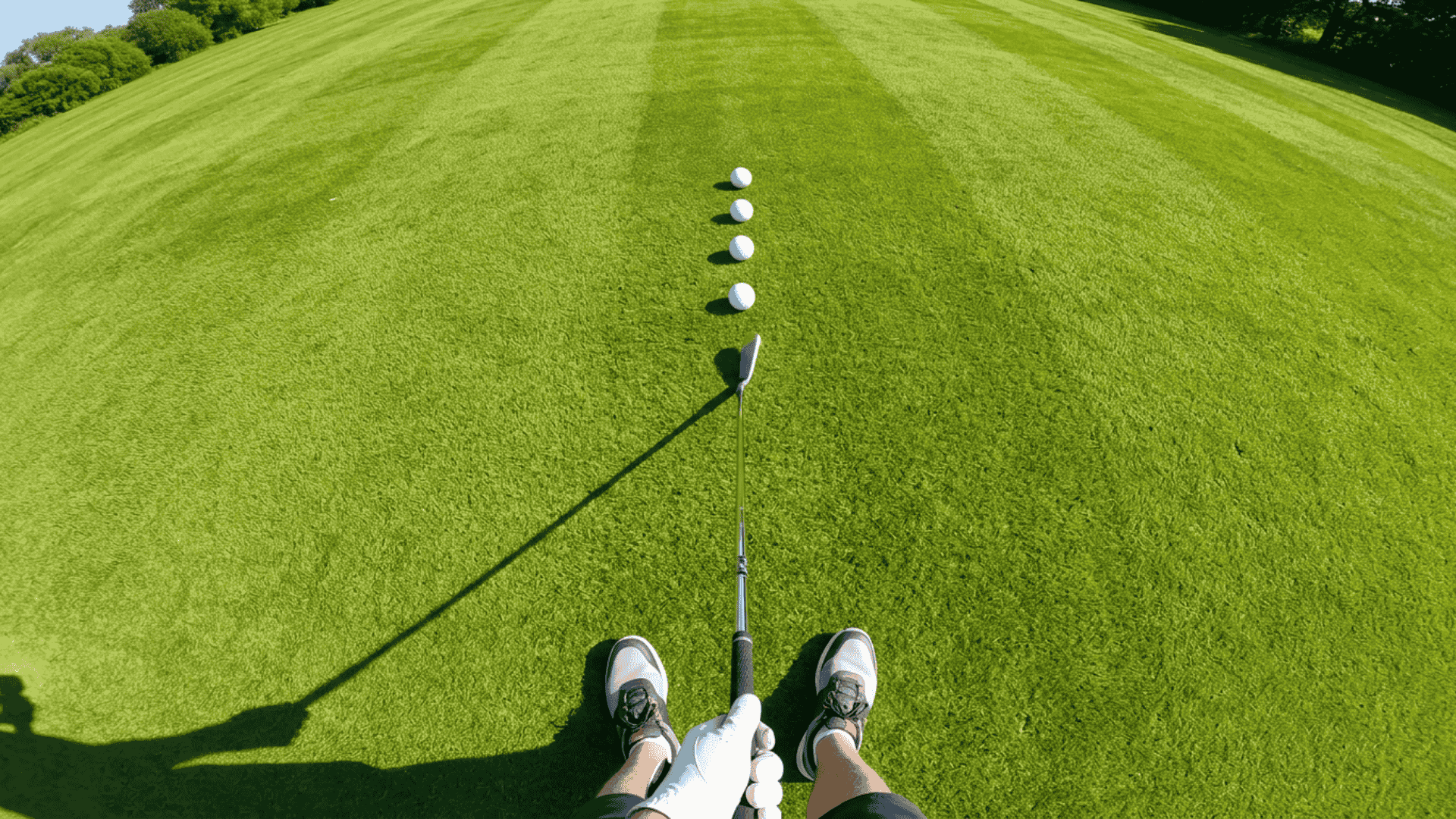 First person view of a golfer lining up golf balls for iron shot practice on a fairway.