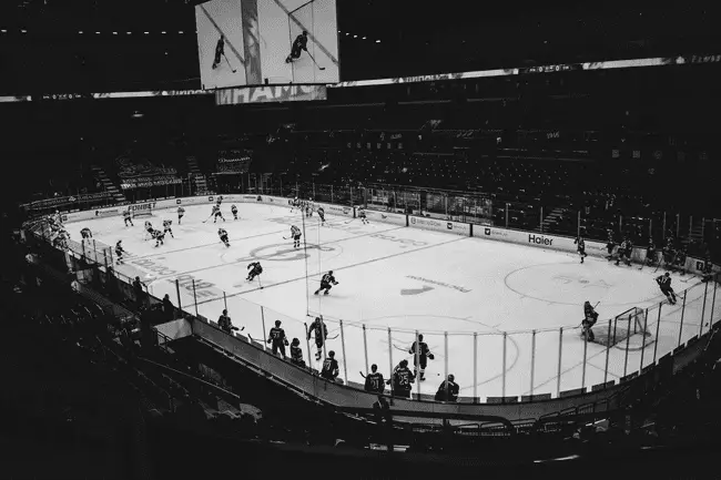 Hockey players practicing on an indoor ice rink under bright arena lights