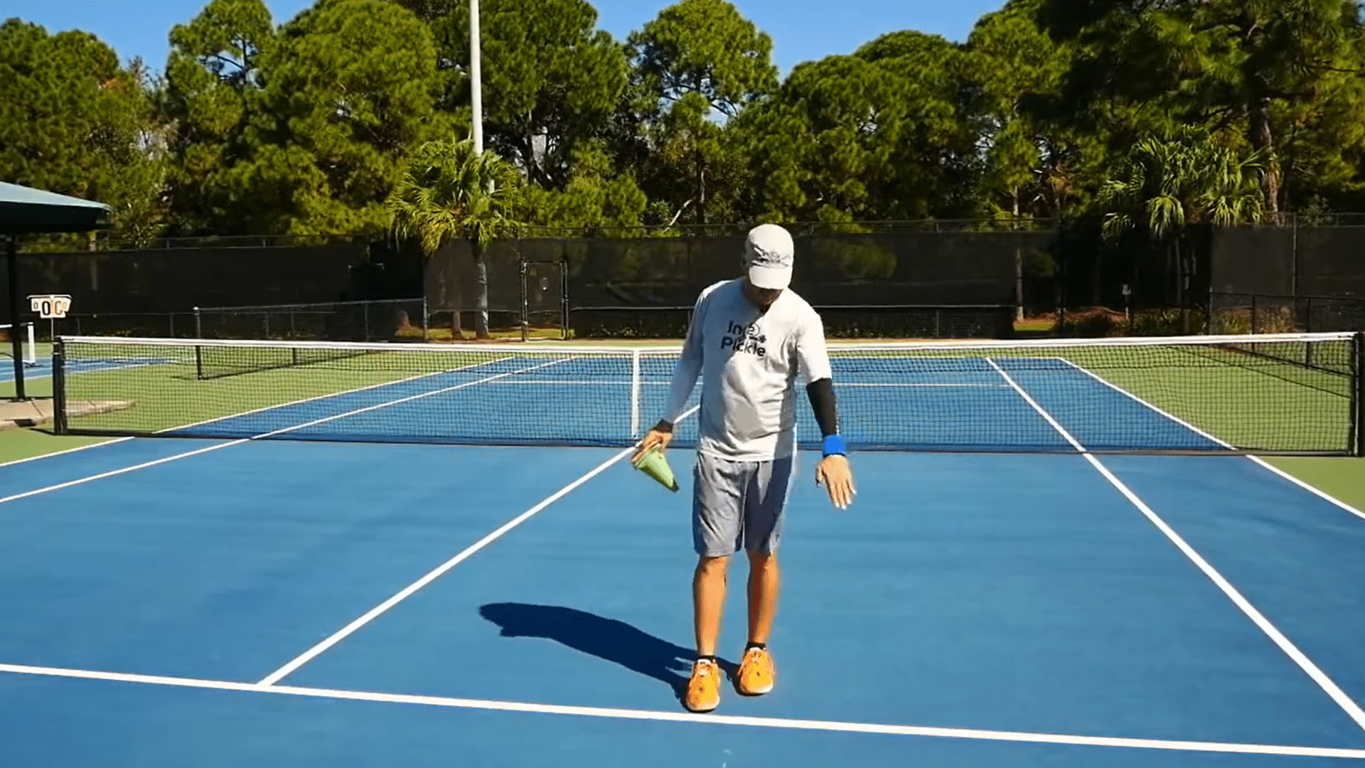 Man measuring court boundaries while setting up temporary pickleball lines on a tennis court