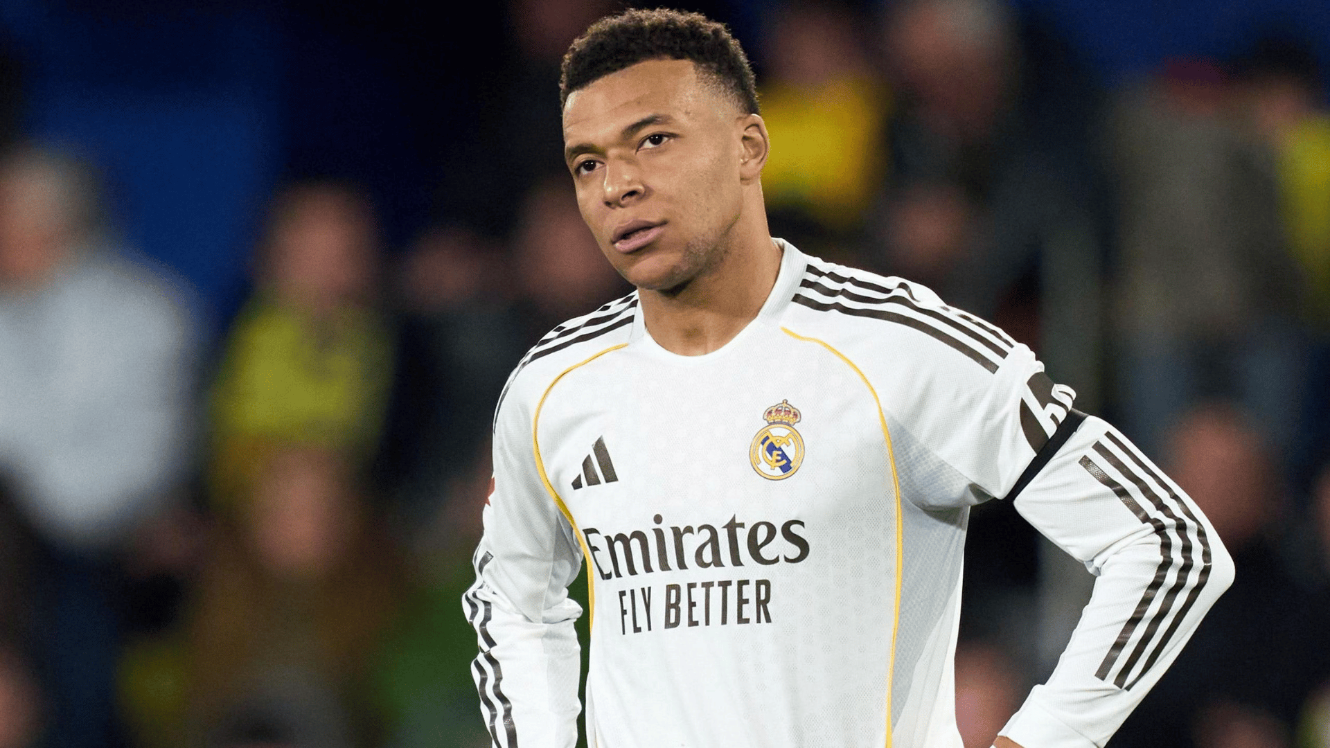 mbappe wearing a black club jersey standing on the field during a stadium match