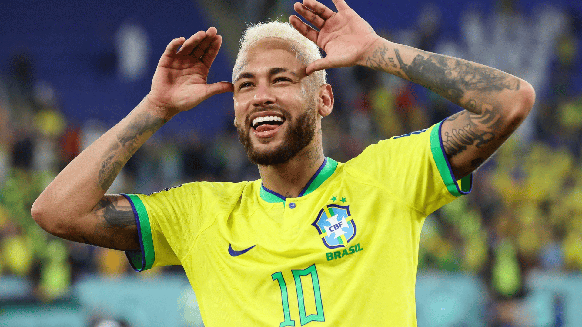 neymar Jr. wearing yellow national team jersey celebrating with arms raised during a match in stadium
