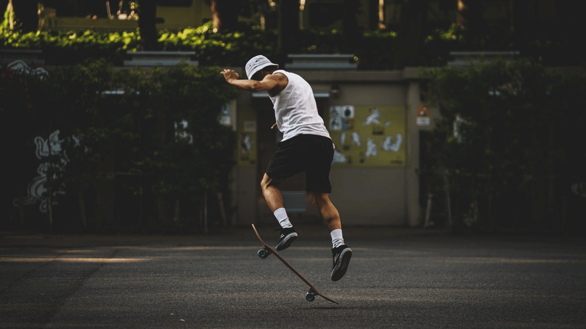person performing a skateboard trick in an open paved area while wearing casual sportswear and balancing in midair