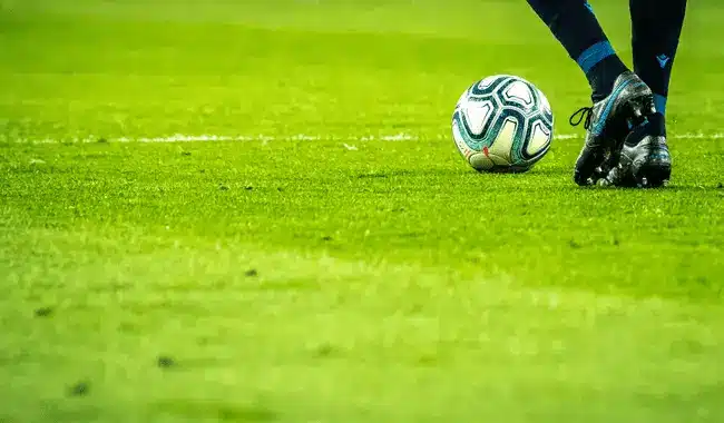 Soccer player in blue uniform dribbling ball on green field during match