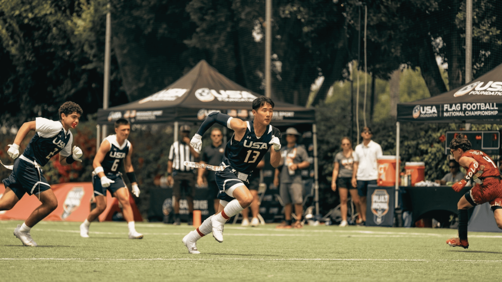 usa flag football player runs with the ball as teammates follow while a defender in red prepares to make a stop