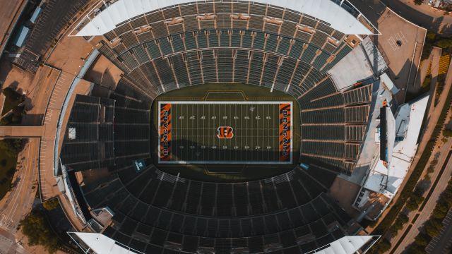 Aerial view of empty outdoor football stadium with green field and surrounding seating areas