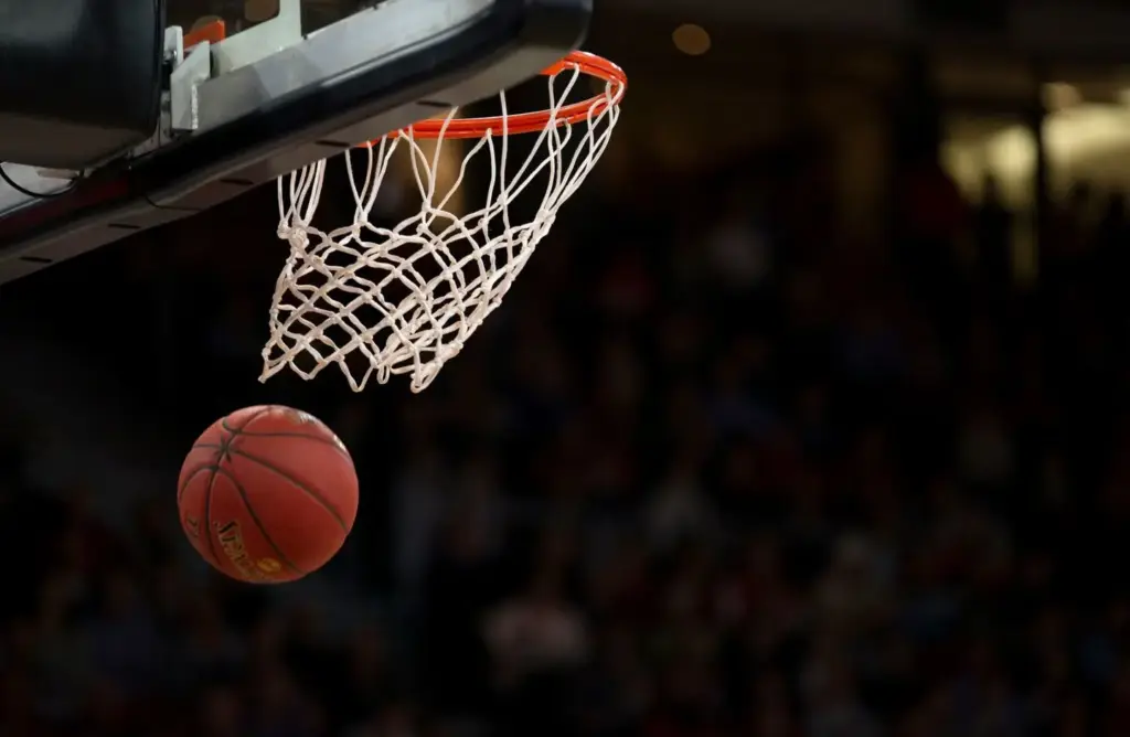 Basketball approaching hoop in indoor stadium during game