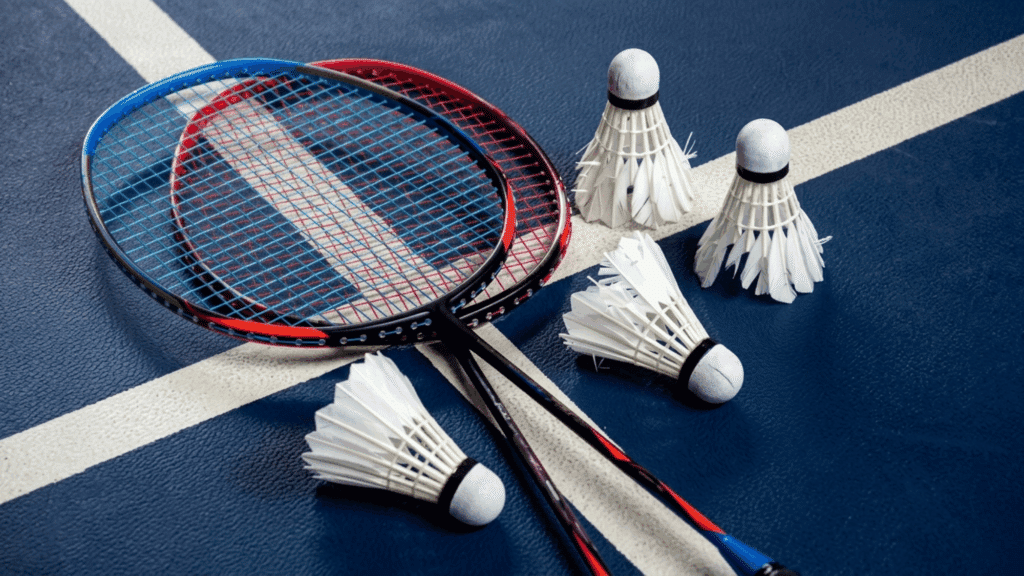 badminton rackets and shuttlecocks placed on an indoor court surface with playing lines visible