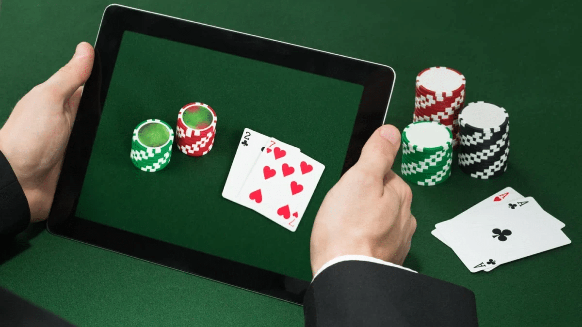 Person holding tablet displaying poker game with chips and playing cards in a casino setting