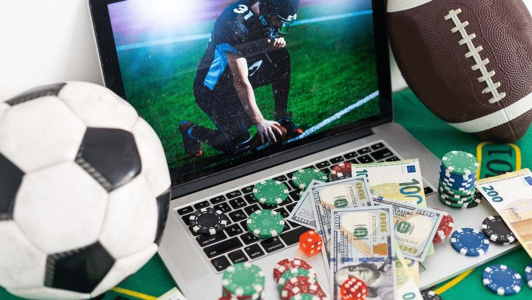 Laptop displaying football player next to soccer ball, poker chips, and dollar bills