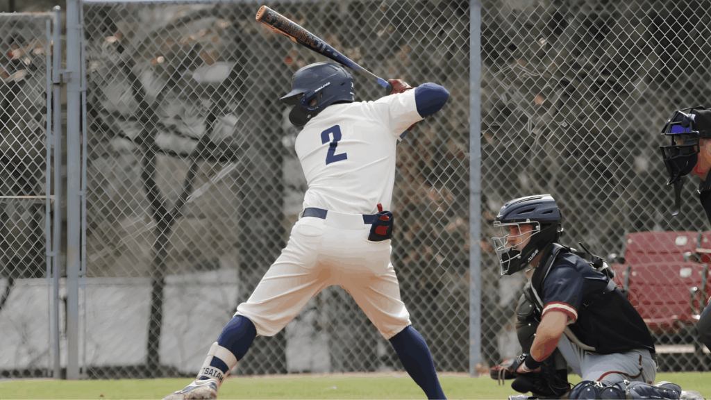 college baseball player batting during a game with catcher and field background