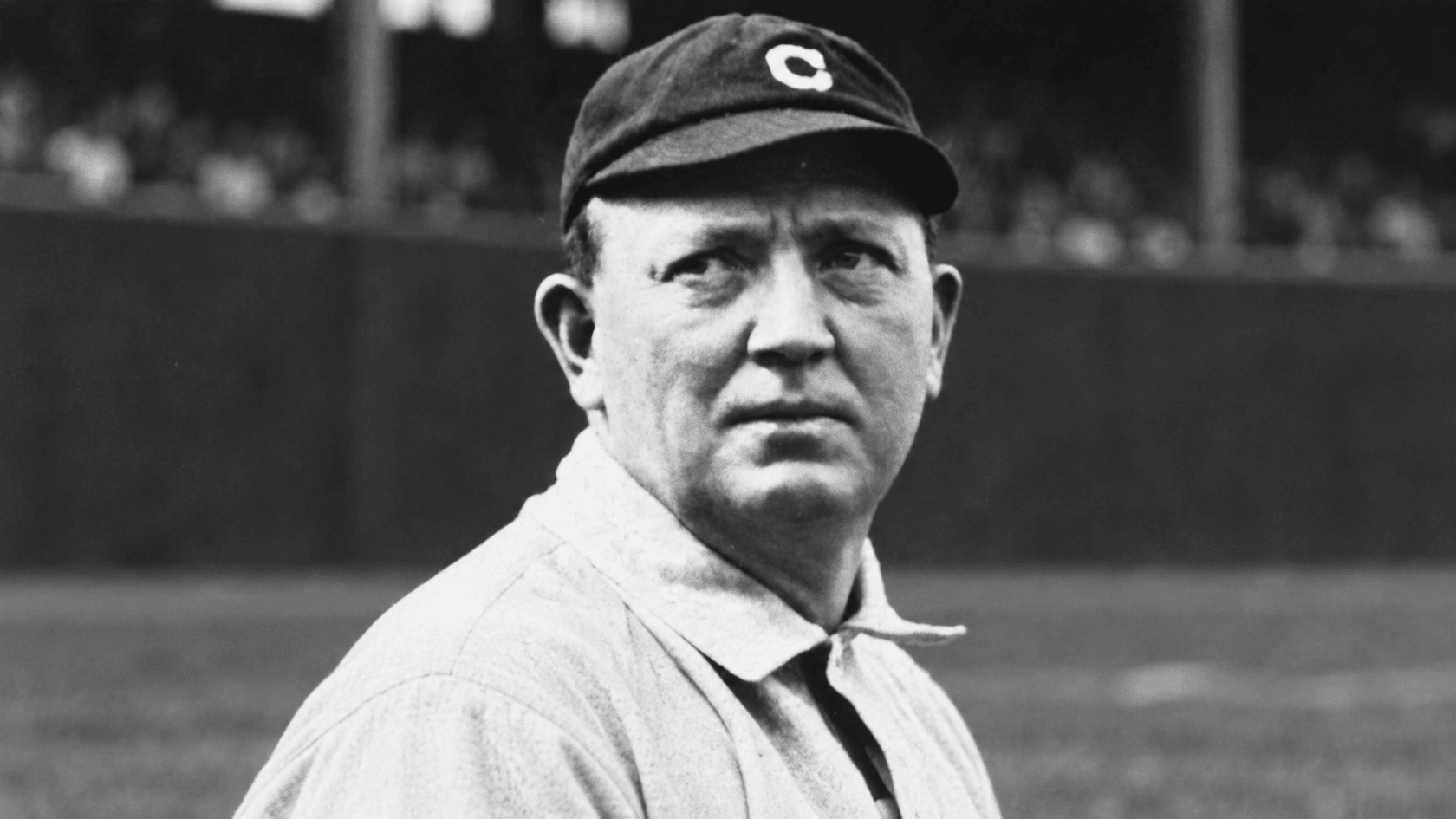 black and white portrait of an early baseball pitcher wearing a dark cap and classic uniform