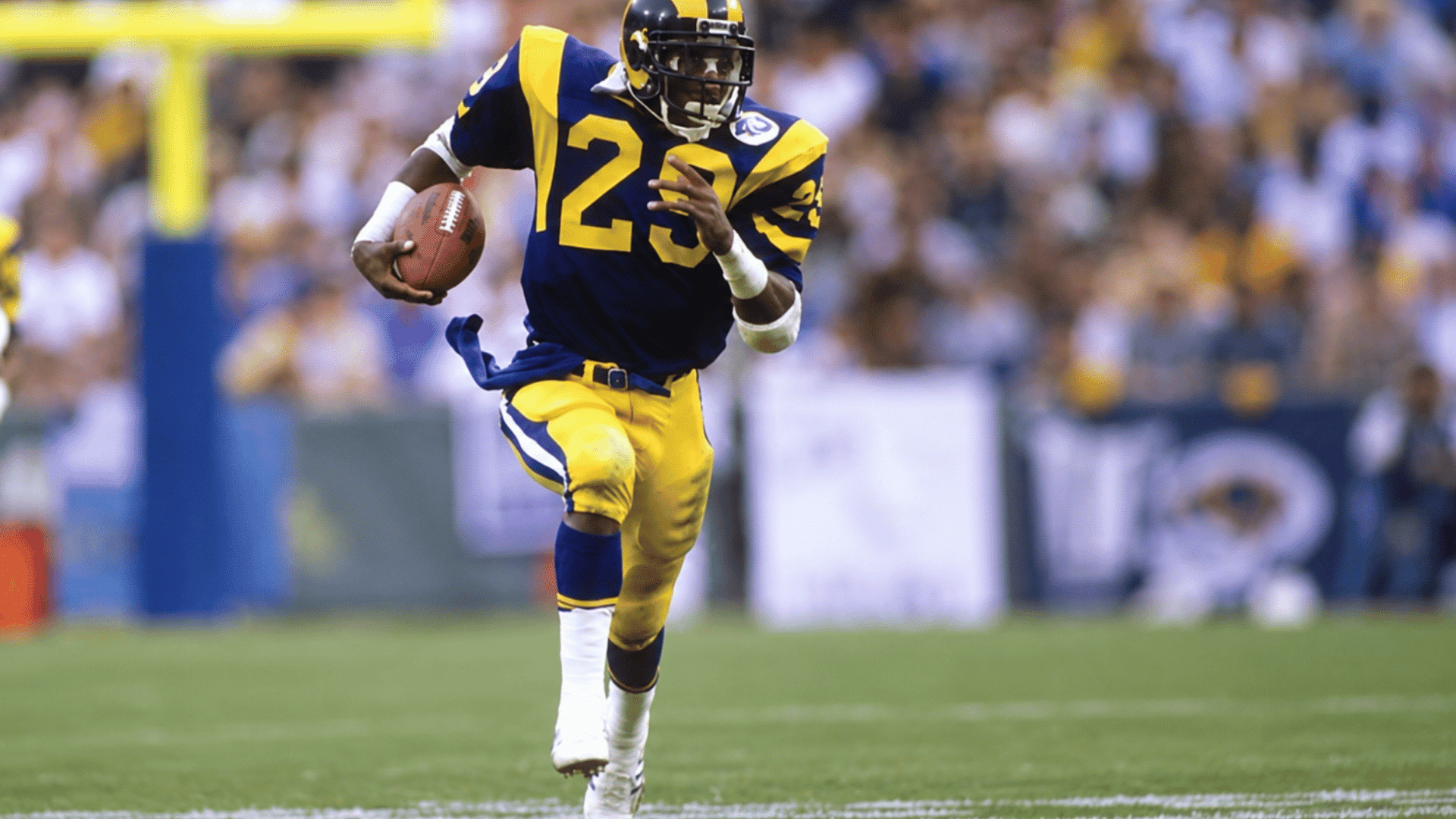 football player wearing number 23 running with the ball across the field during a game