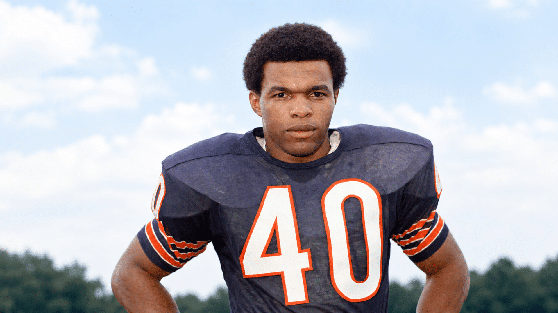 football player wearing a navy number 40 jersey standing outdoors against a bright blue sky