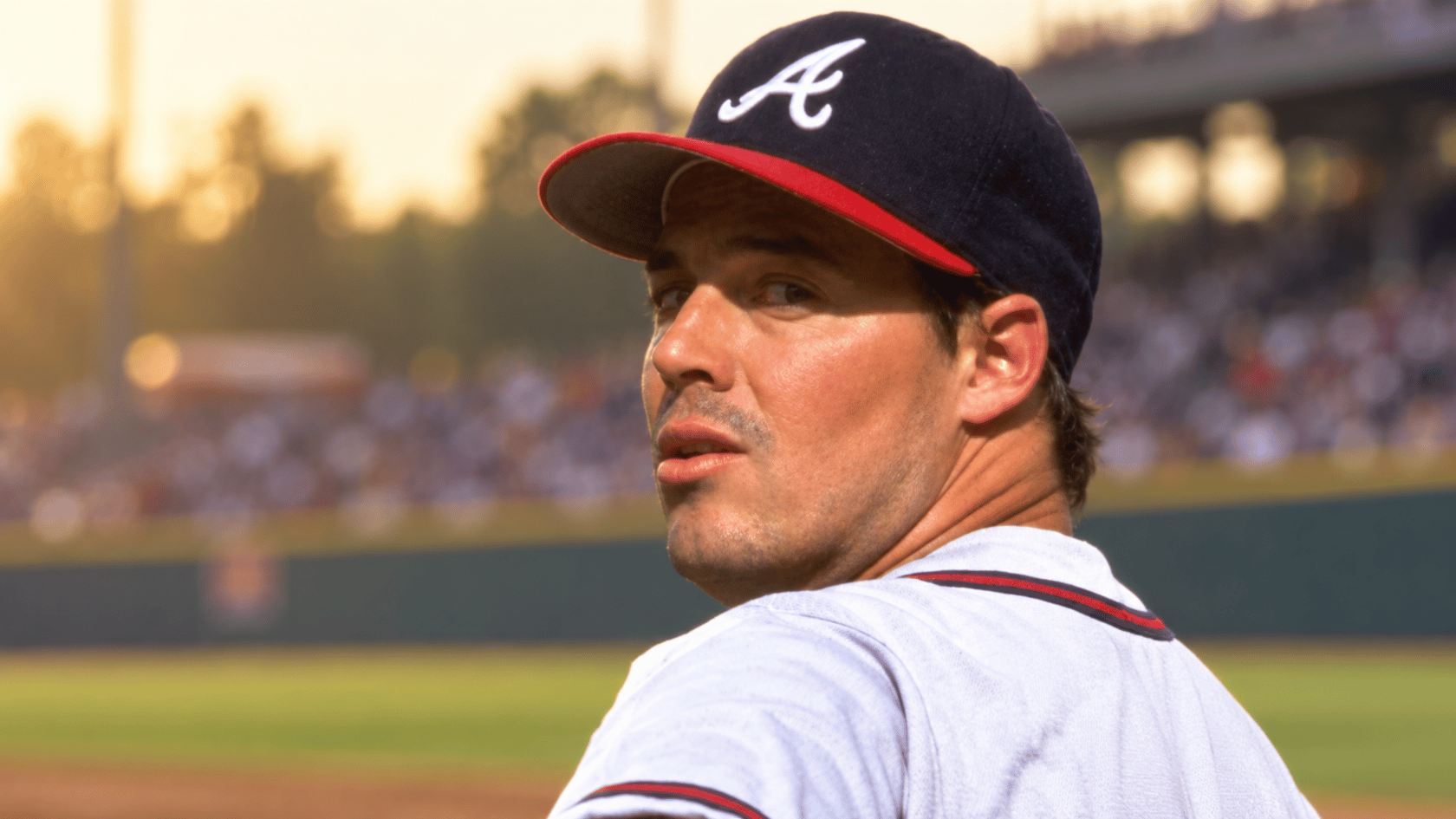 close up of an Atlanta baseball pitcher wearing a dark cap with a red brim on the field