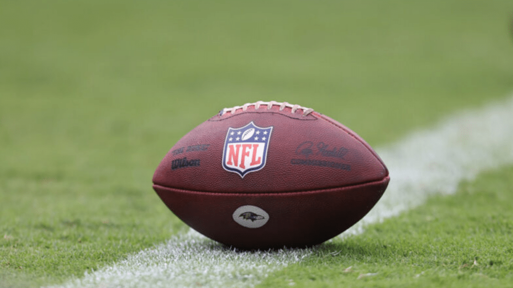 nfl football resting on green field with yard line markings and stadium sports background