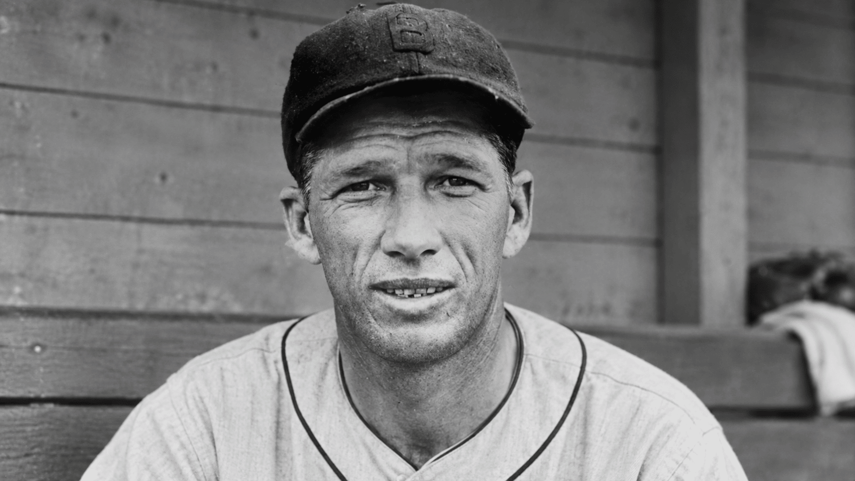 vintage black and white close up of a baseball pitcher wearing a dark cap and classic uniform