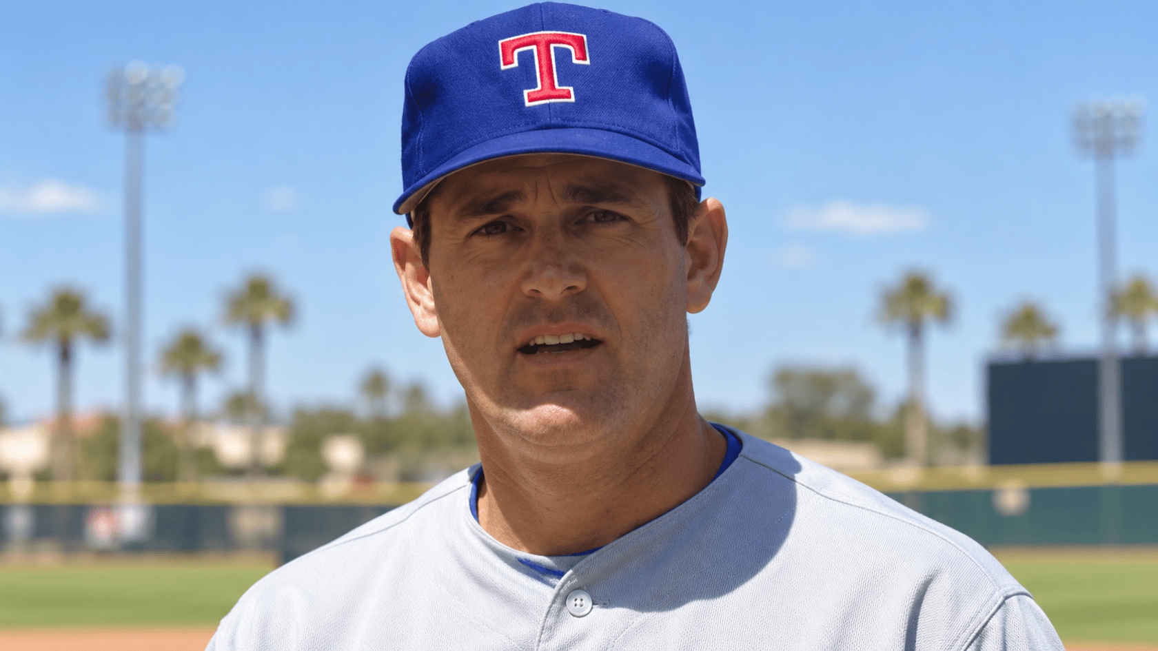texas baseball pitcher wearing a blue team cap and gray uniform while standing on the baseball field