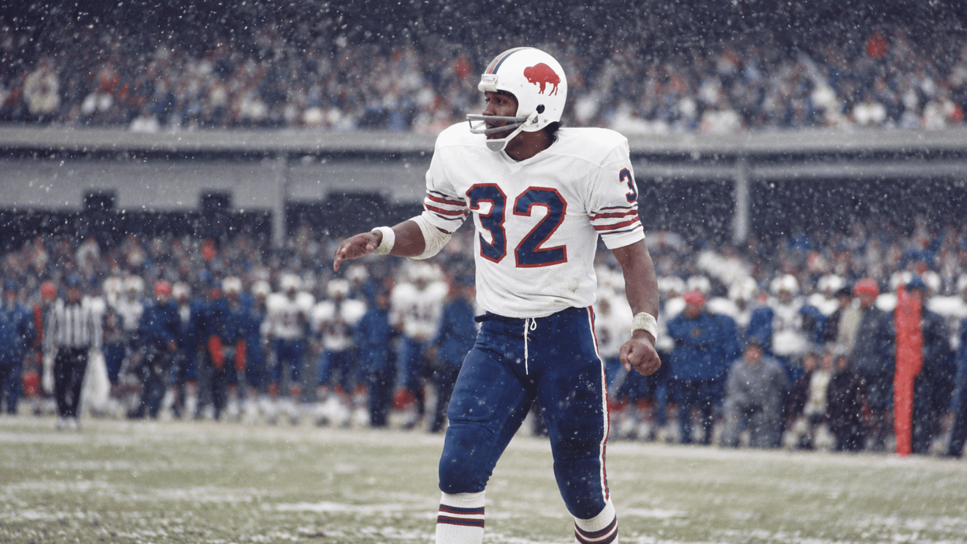 football player wearing number 32 standing on a snowy field during a game with a crowded stadium in the background