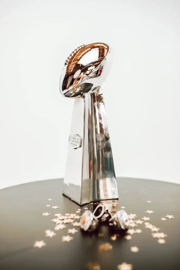 Silver trophy resembling an American football on a pedestal surrounded by scattered star confetti