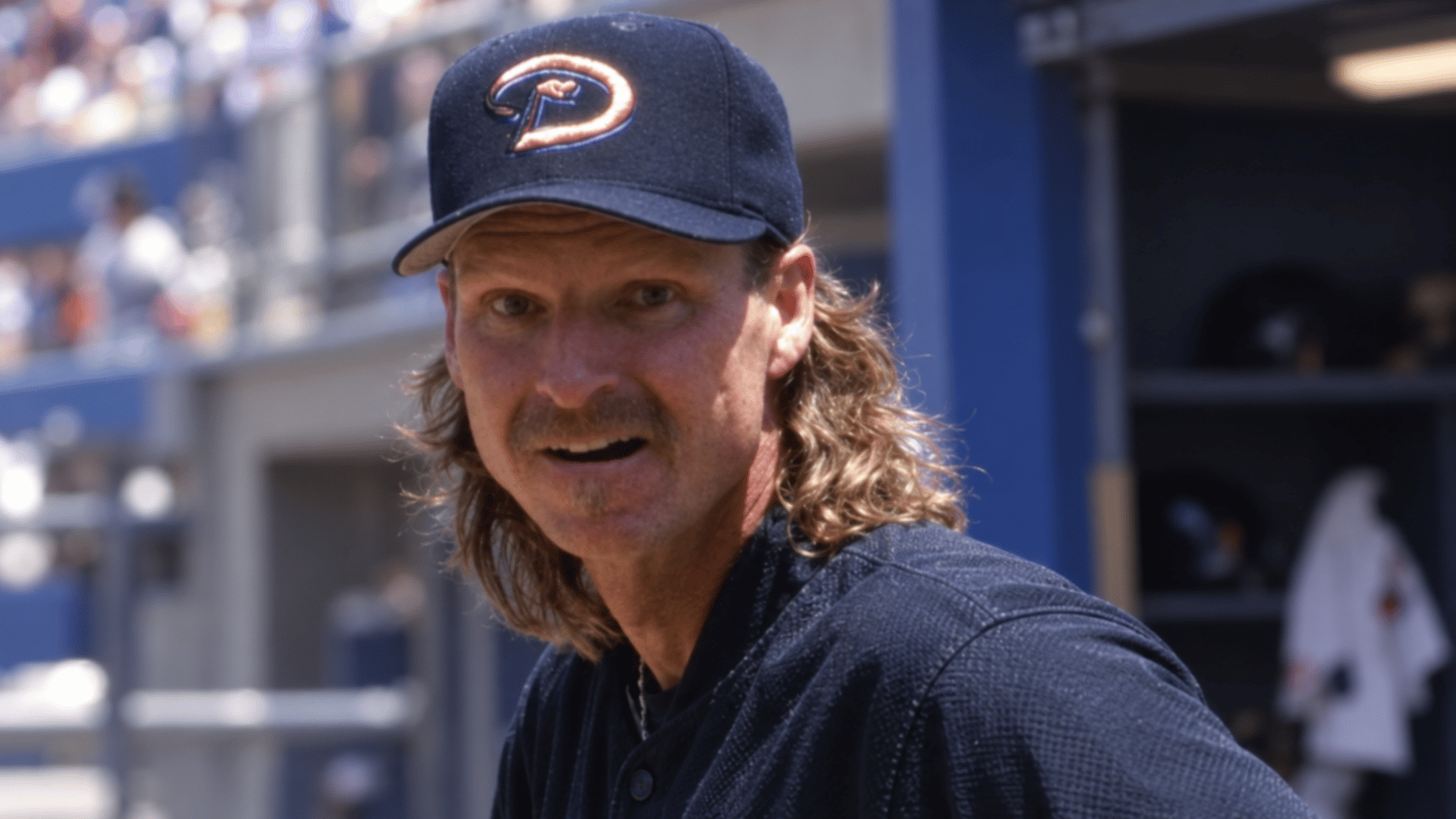 baseball pitcher wearing an arizona cap with long hair and a mustache during a game