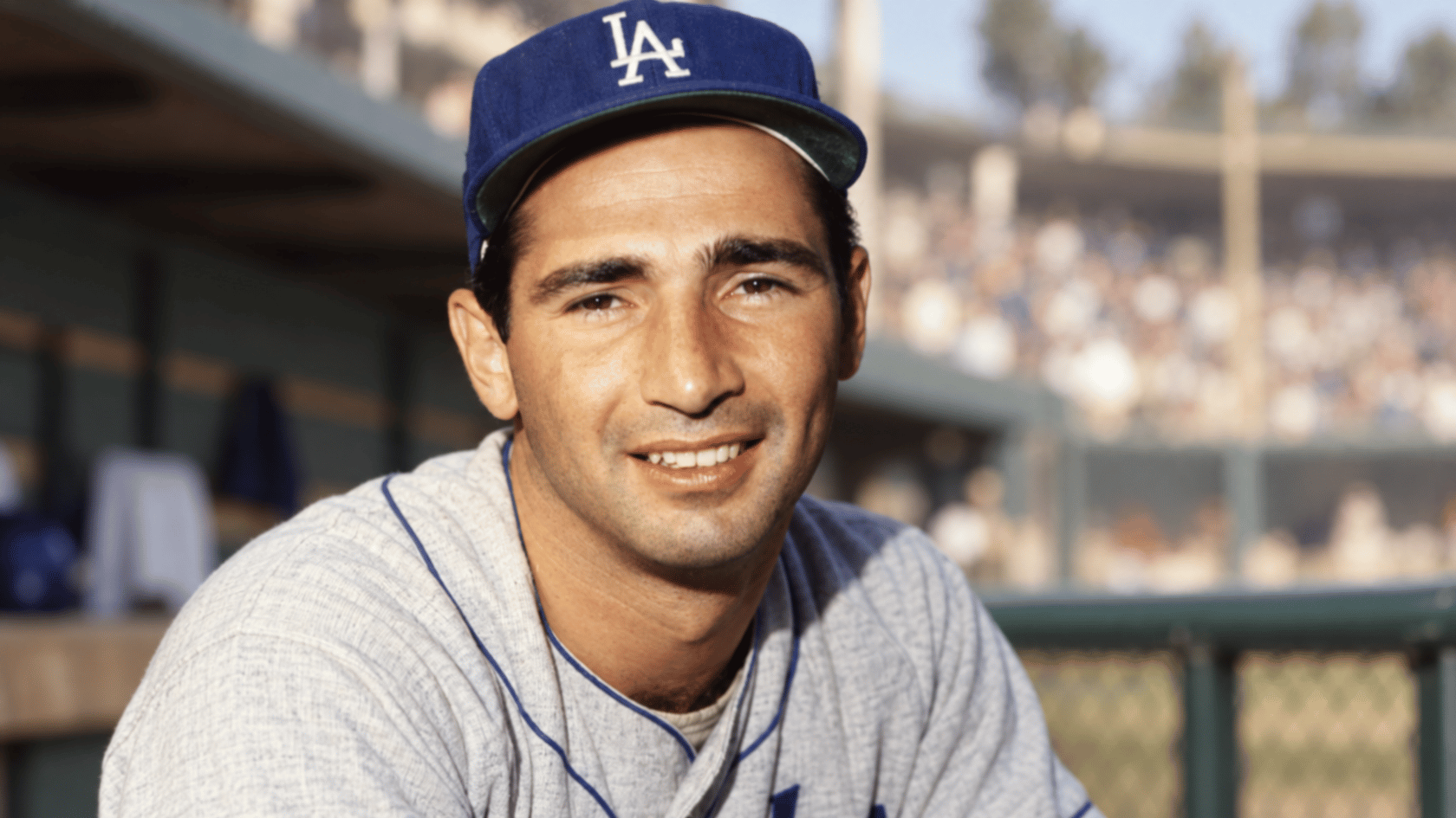 los angeles baseball pitcher wearing a blue team cap while sitting near the dugout at a ballpark